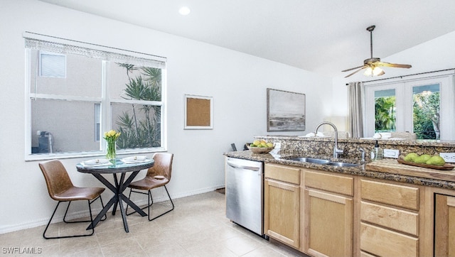 kitchen with dishwasher, lofted ceiling, sink, dark stone counters, and light brown cabinets