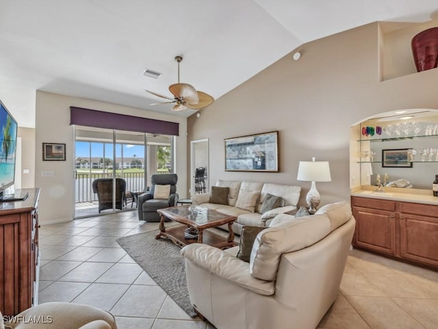 living area with light tile patterned floors, ceiling fan, indoor bar, and visible vents