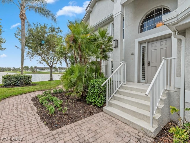 entrance to property featuring a water view and stucco siding