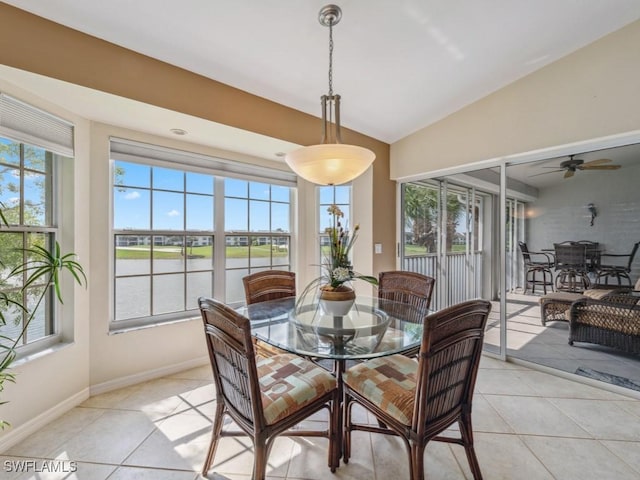 dining room with a healthy amount of sunlight, light tile patterned floors, and vaulted ceiling