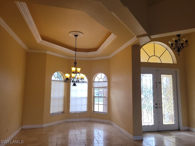 entrance foyer featuring french doors, a tray ceiling, crown molding, and a notable chandelier