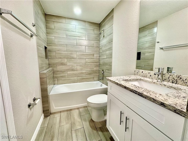 full bathroom with tiled shower / bath, vanity, and toilet