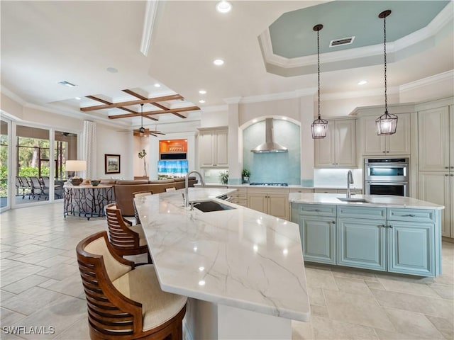 kitchen with a spacious island, sink, light stone counters, appliances with stainless steel finishes, and pendant lighting