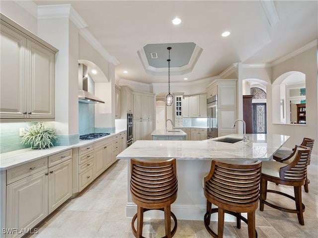 kitchen featuring decorative light fixtures, sink, wall chimney exhaust hood, stainless steel appliances, and a spacious island