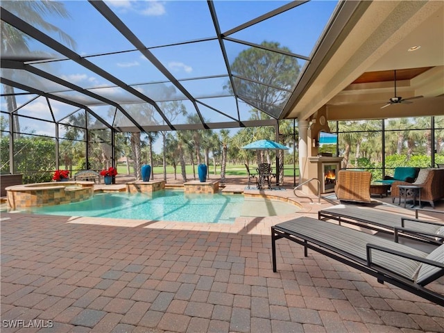 view of pool with exterior fireplace, an in ground hot tub, a lanai, ceiling fan, and a patio area