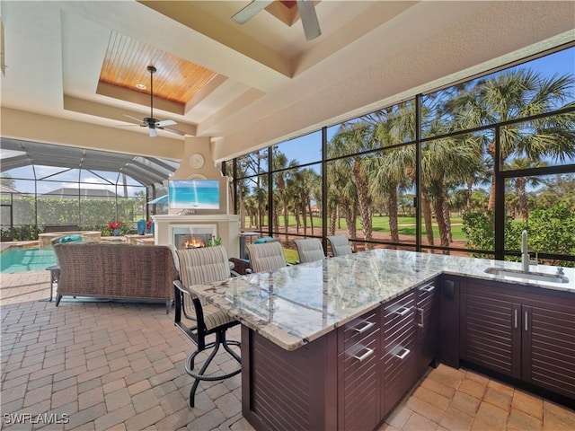 view of patio / terrace featuring an outdoor living space with a fireplace, ceiling fan, and an outdoor wet bar