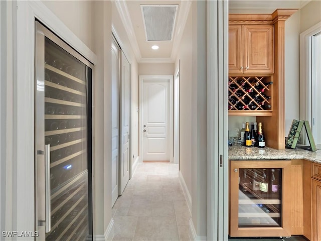 hallway featuring ornamental molding, light tile patterned floors, and beverage cooler