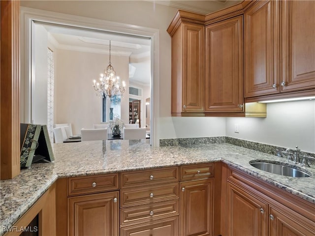 kitchen with crown molding, light stone countertops, sink, and hanging light fixtures