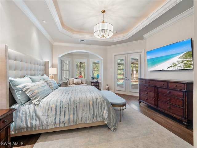 bedroom featuring an inviting chandelier, hardwood / wood-style floors, a tray ceiling, ornamental molding, and access to outside