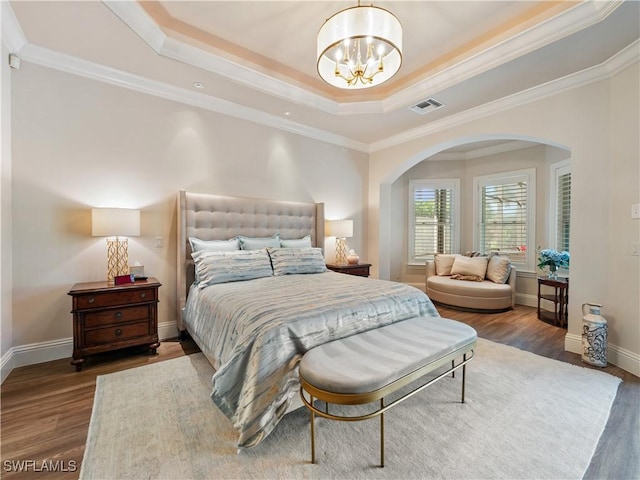 bedroom featuring a raised ceiling, ornamental molding, hardwood / wood-style flooring, and a notable chandelier