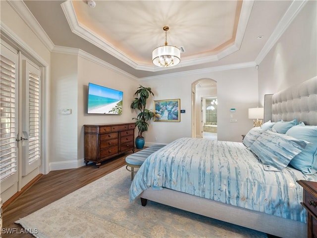 bedroom with crown molding, ensuite bathroom, dark hardwood / wood-style flooring, a raised ceiling, and a chandelier