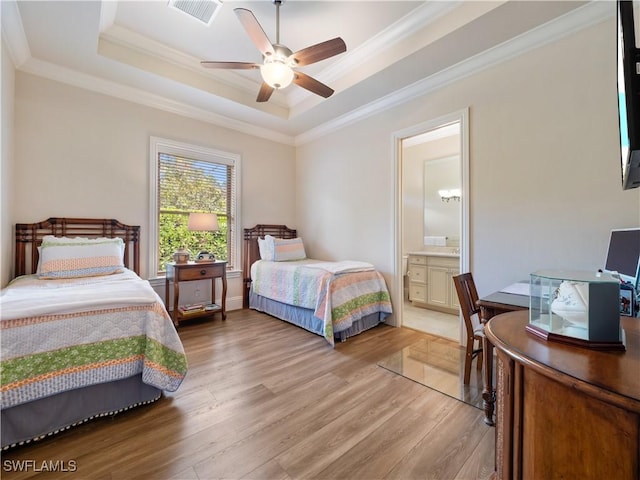 bedroom with ensuite bathroom, ornamental molding, a tray ceiling, ceiling fan, and light hardwood / wood-style floors