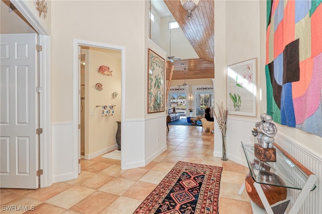 hall featuring light tile patterned floors and a towering ceiling