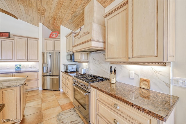 kitchen with lofted ceiling, premium range hood, dark stone countertops, stainless steel appliances, and tasteful backsplash