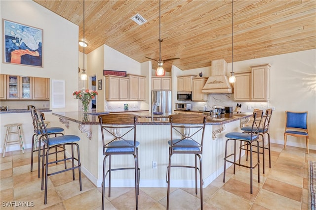 kitchen with dark stone counters, a kitchen breakfast bar, stainless steel fridge with ice dispenser, and custom range hood