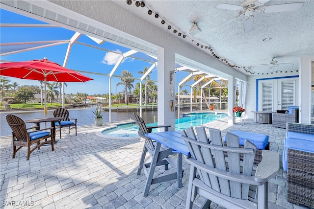 view of patio / terrace with a lanai, ceiling fan, and a water view