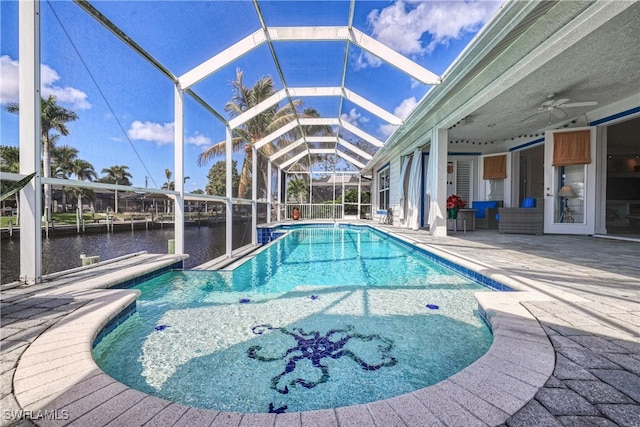 view of swimming pool with a water view, ceiling fan, a lanai, and a patio