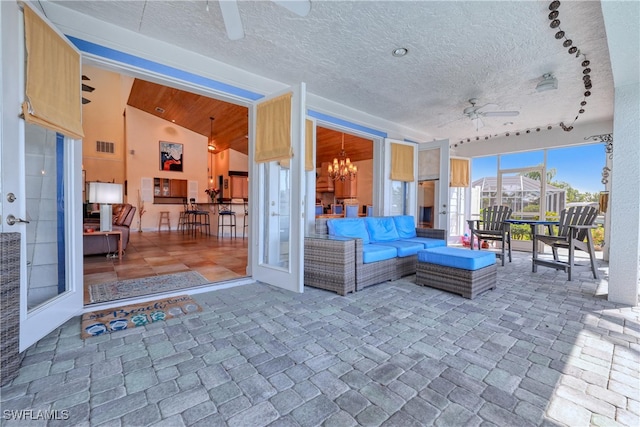 view of patio with ceiling fan, an outdoor hangout area, and glass enclosure