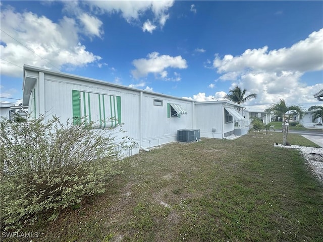 view of property exterior with central AC unit and a lawn