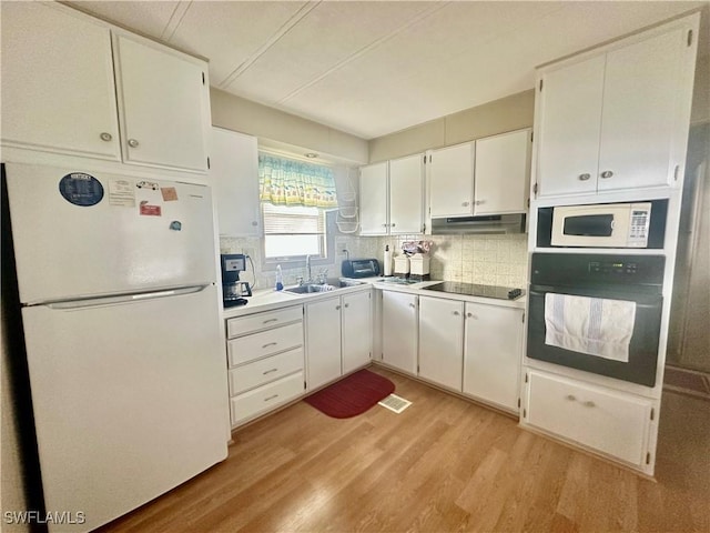 kitchen featuring white cabinetry, a sink, under cabinet range hood, and black appliances