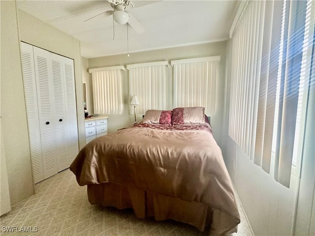 bedroom with ceiling fan, a closet, and light colored carpet