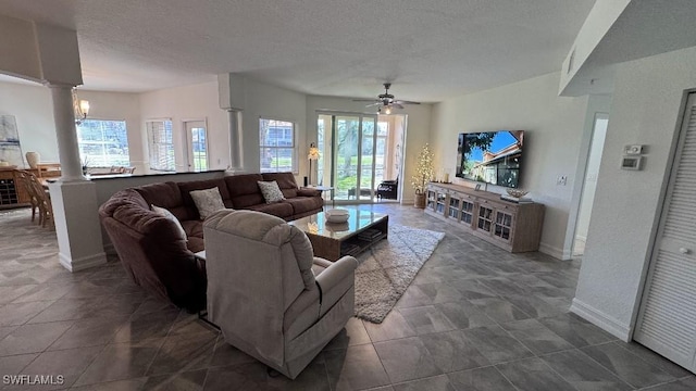 tiled living room featuring decorative columns, ceiling fan, and a textured ceiling