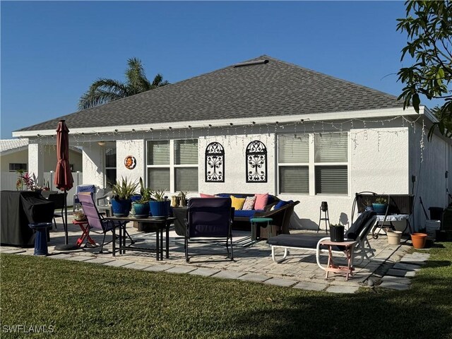 back of property with a shingled roof, a patio, and stucco siding