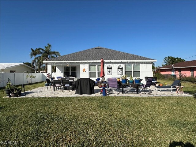 rear view of property featuring a lawn, a patio area, and a fenced backyard