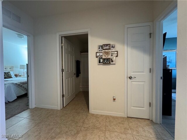 corridor with visible vents, baseboards, and light tile patterned floors