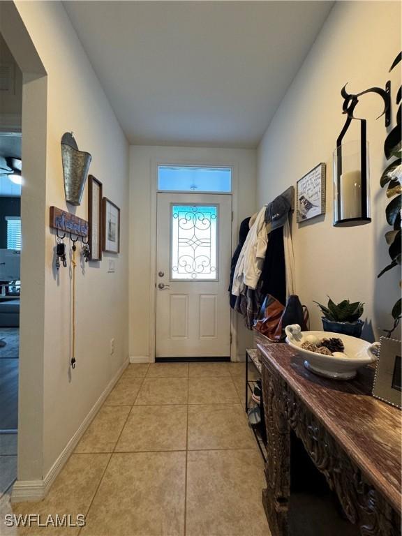 doorway with light tile patterned flooring and baseboards