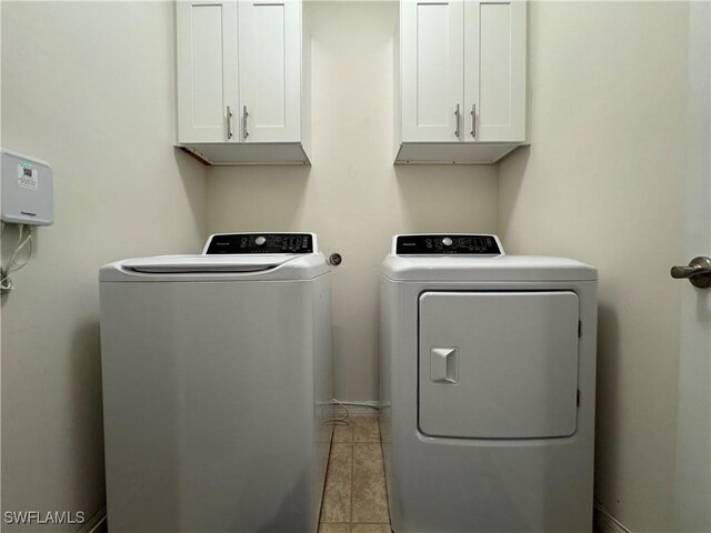 laundry room featuring baseboards, light tile patterned flooring, cabinet space, and washer and dryer