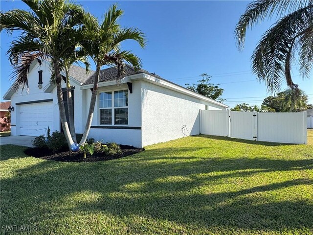 view of side of property featuring a yard, fence, a gate, and stucco siding