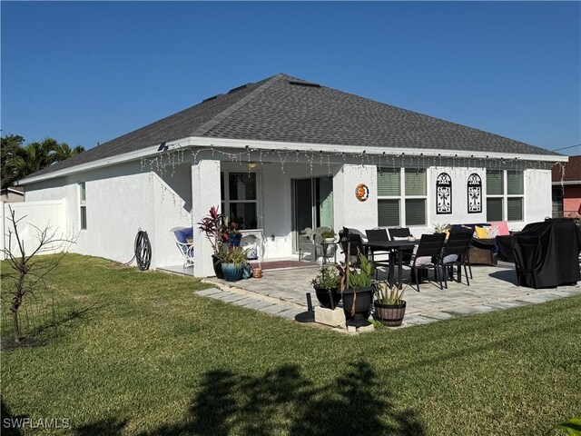 back of house featuring a patio, a lawn, and roof with shingles