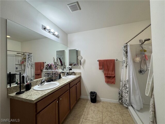 bathroom featuring a tile shower, a sink, visible vents, and tile patterned floors