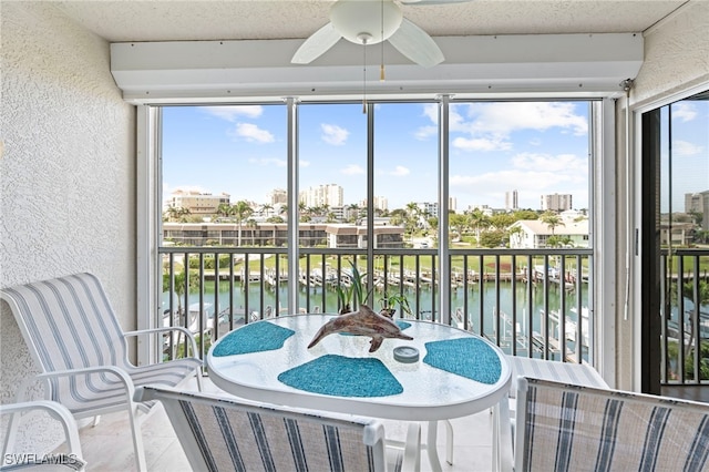 sunroom / solarium featuring a water view and ceiling fan