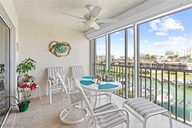 sunroom with a water view and ceiling fan