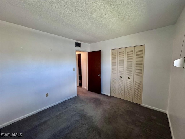 unfurnished bedroom with dark carpet, a closet, and a textured ceiling