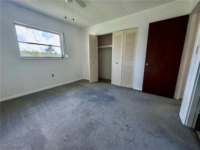 unfurnished bedroom with ceiling fan, a closet, a textured ceiling, and dark colored carpet