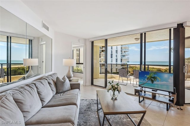 living room featuring light tile patterned floors, expansive windows, a healthy amount of sunlight, and a water view