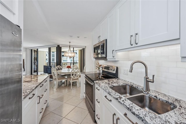 kitchen featuring sink, white cabinetry, stainless steel appliances, tasteful backsplash, and decorative light fixtures