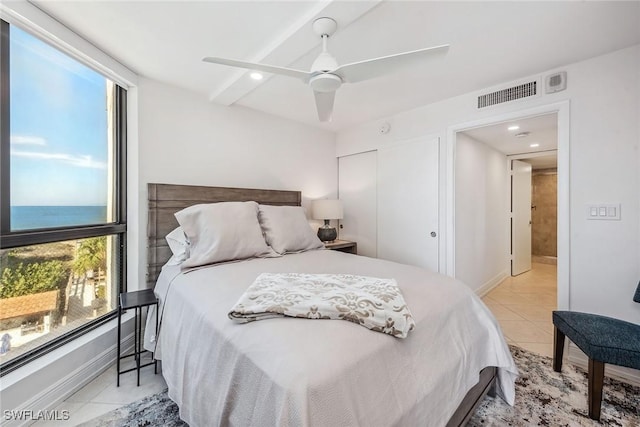 bedroom with a water view, ceiling fan, a closet, and light tile patterned floors