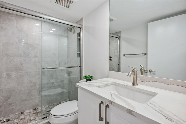 bathroom featuring vanity, toilet, and a shower with door