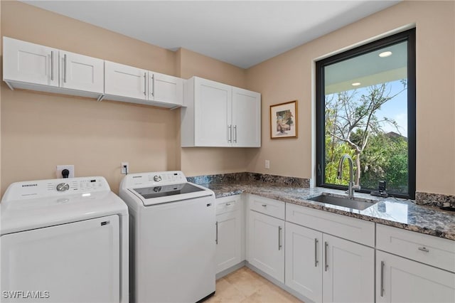 washroom with cabinets, washing machine and dryer, and sink