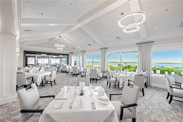 dining area featuring lofted ceiling with beams, a water view, a healthy amount of sunlight, and carpet