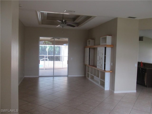 empty room featuring light tile patterned floors, a tray ceiling, and ceiling fan