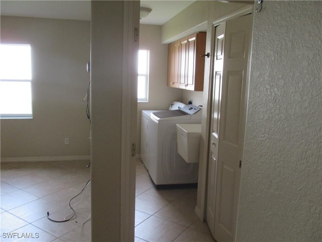 clothes washing area featuring cabinets, light tile patterned floors, and washer and dryer