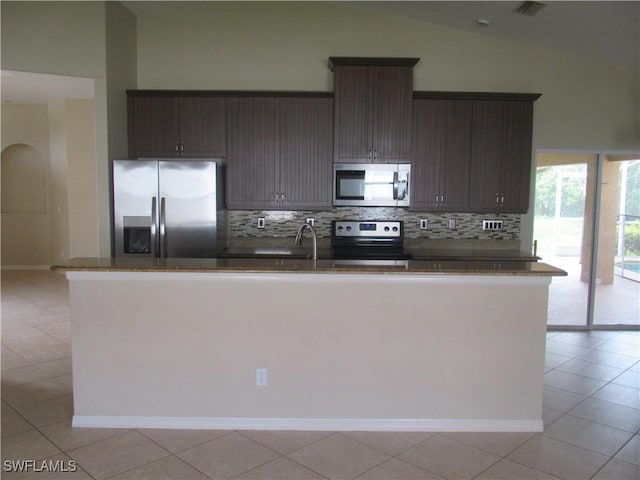 kitchen featuring light tile patterned floors, stainless steel appliances, high vaulted ceiling, dark brown cabinetry, and tasteful backsplash