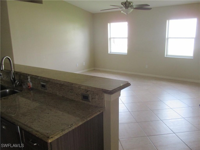 kitchen with stone countertops, sink, light tile patterned floors, and ceiling fan