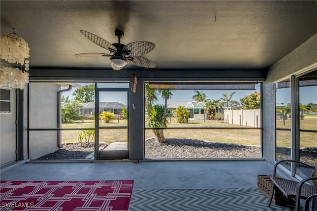 unfurnished sunroom with ceiling fan