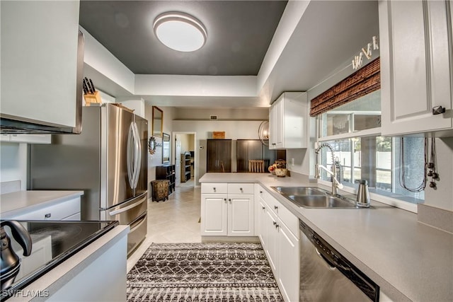 kitchen featuring white cabinetry, stove, sink, a tray ceiling, and stainless steel dishwasher